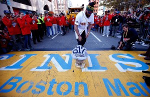 Jonny Gomes #5 of the Boston Red Sox lays the World Series trophy and the 'Boston Strong 617' jersey onto the finish line of the Boston Marathon on Boylston Street during the World Series victory parade on November 2, 2013 in Boston, Massachusetts.  (Jared Wickerham/Getty Images)